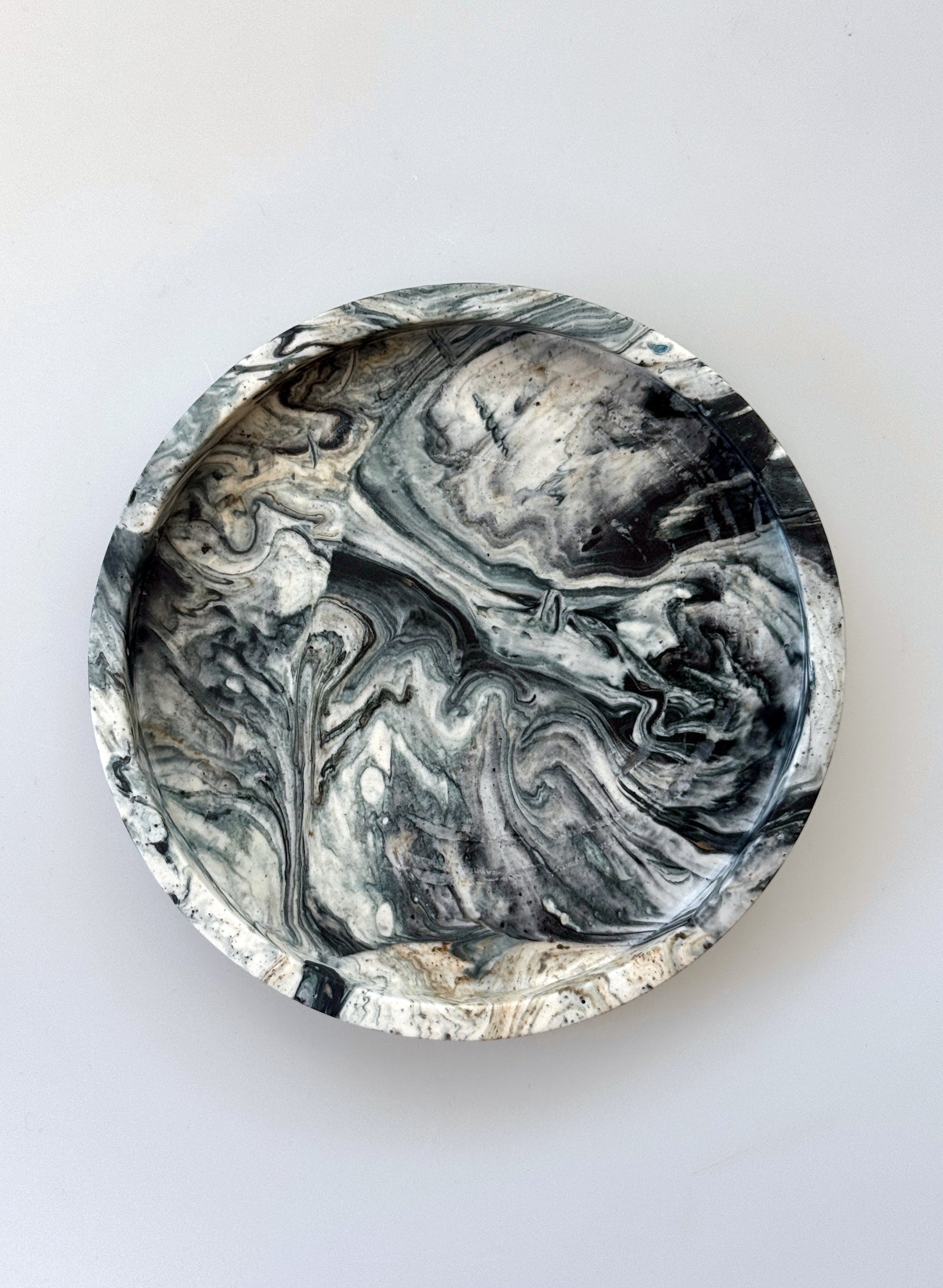 Round marbleized coaster with black and gray patterns on a white background