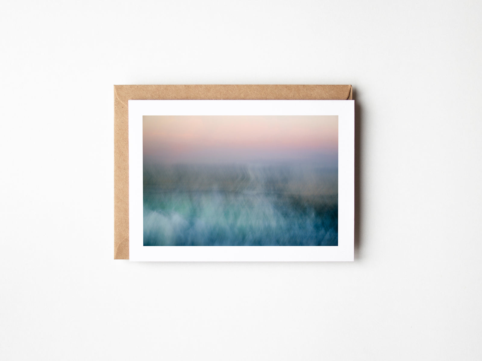 A fine art greeting card with a printed image of a landscape on it, accompanied by a brown envelope.