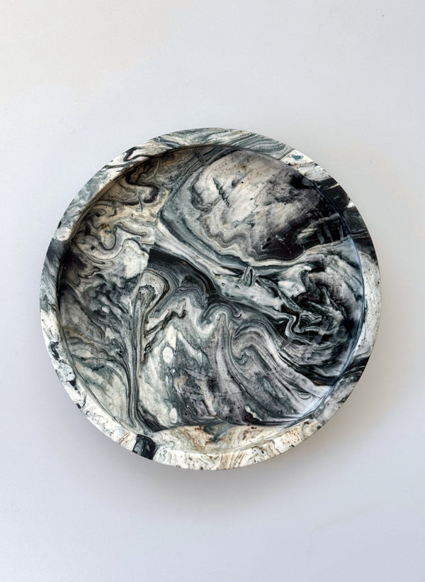 Round marbleized coaster with black and gray patterns on a white background