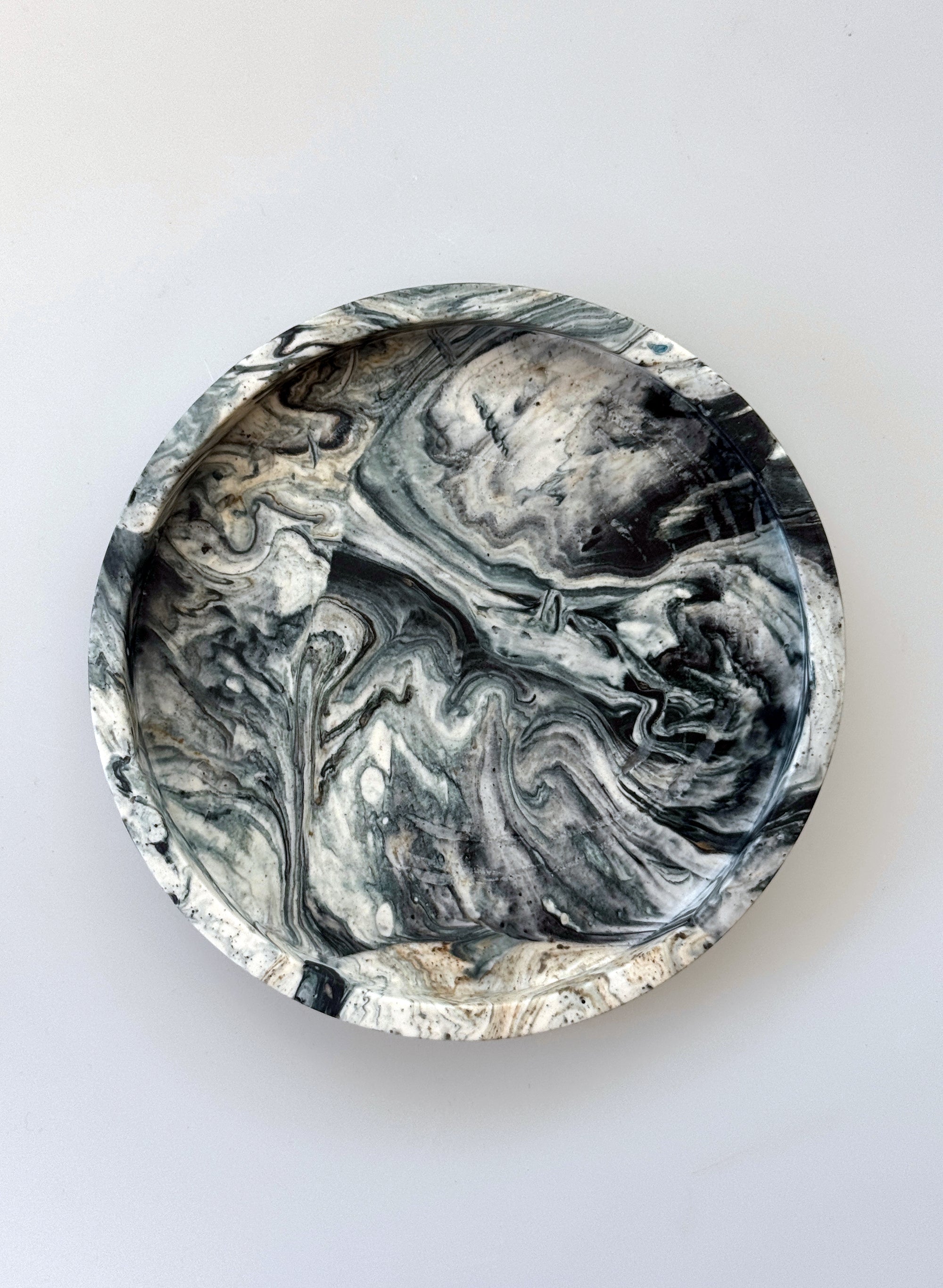 Round marbleized coaster with black and gray patterns on a white background